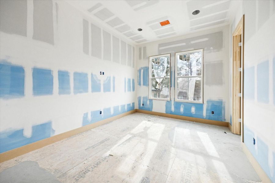 The secondary bedroom features a balanced layout with ample wall space and natural light from oversized windows.