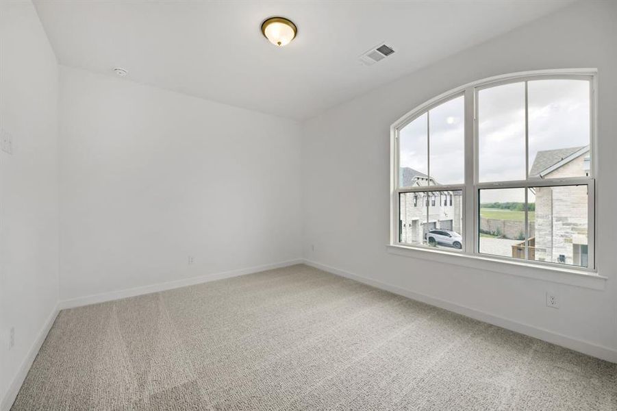 Room featuring an arched window, light-toned carpet, white painted walls, and a ceiling-mounted light fixture Room featuring an arched window, light-toned carpet, white painted walls, and a ceiling-mounted light fixture
