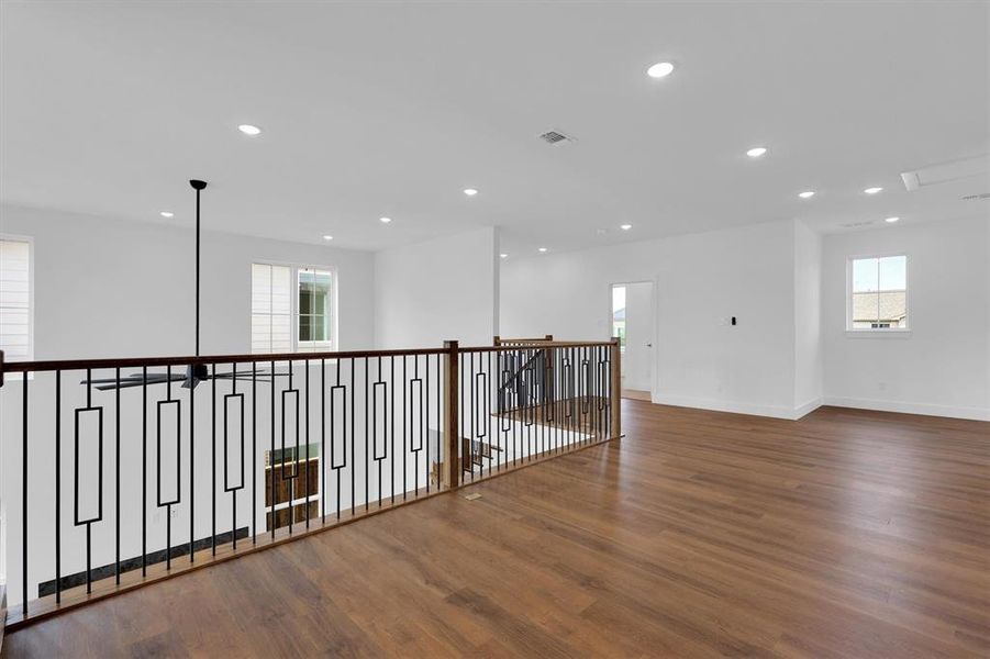 Corridor featuring healthy amount of natural light, wood finished floors, recessed lighting, and an upstairs landing Corridor featuring healthy amount of natural light, wood finished floors, recessed lighting, and an upstairs landing