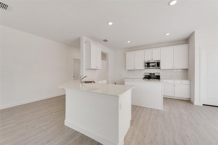 Kitchen featuring white cabinets, decorative backsplash, sink, and stainless steel appliances