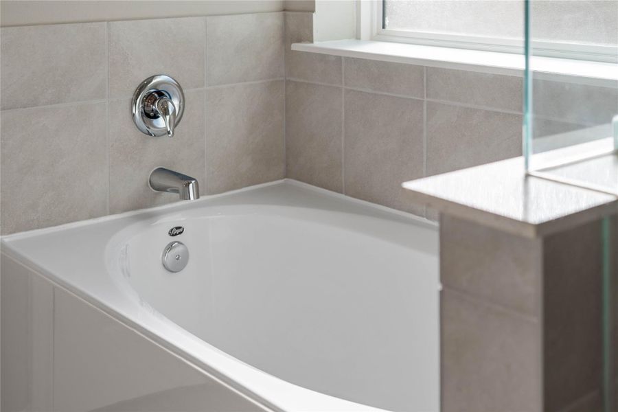 Indulge in the primary bath's deep, built-in soaking tub with elegant chrome fixtures and a sleek tile surround for a true spa-like retreat. Indulge in the primary bath's deep, built-in soaking tub with elegant chrome fixtures and a sleek tile surround for a true spa-like retreat.