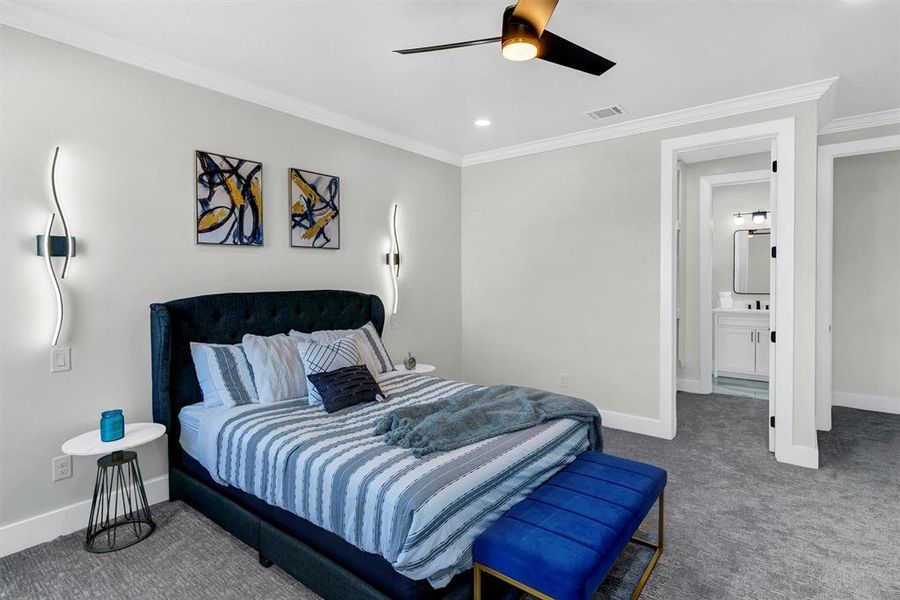 Carpeted bedroom with crown molding, ensuite bath, and ceiling fan