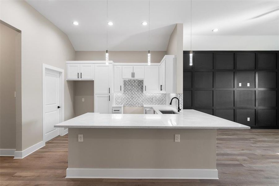 Kitchen featuring pendant lighting, sink, white cabinetry, and tasteful backsplash