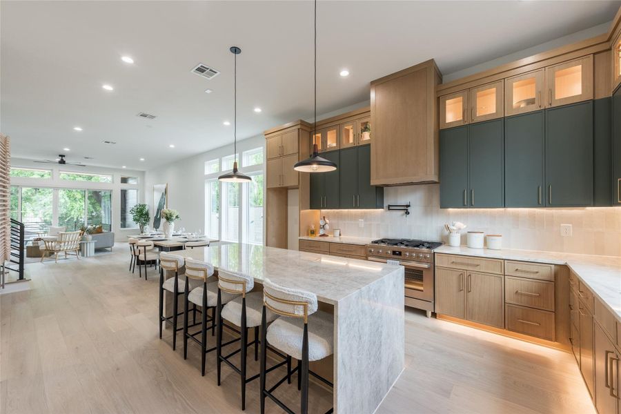 Light travels the full length of the floor plan here. Starting at the window wall, crossing oak planking, catching the polished edge of the island, finishing on the glass uppers. A kitchen designed to inherit the room's daylight rather than fight it.