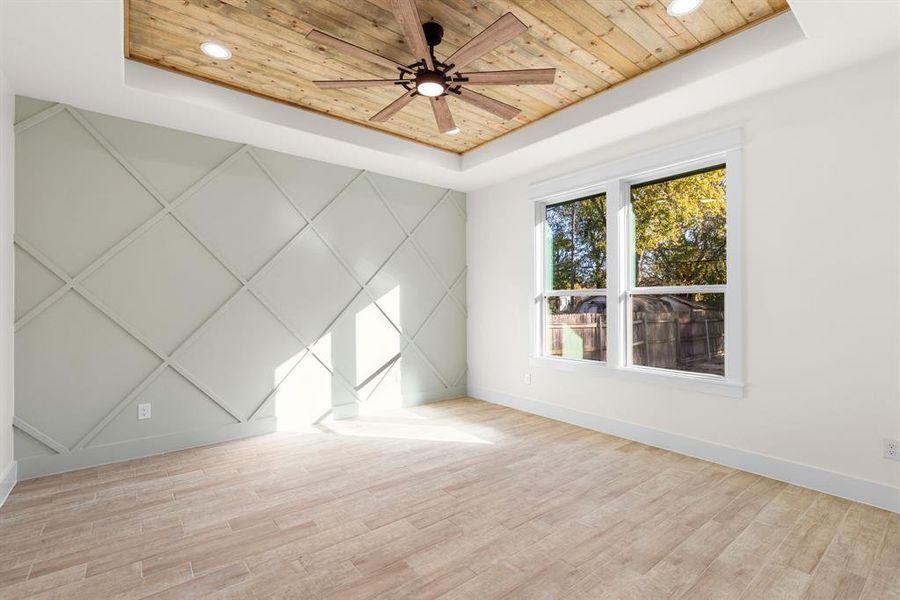 Empty room featuring wooden ceiling, a tray ceiling, ceiling fan, and light hardwood / wood-style floors