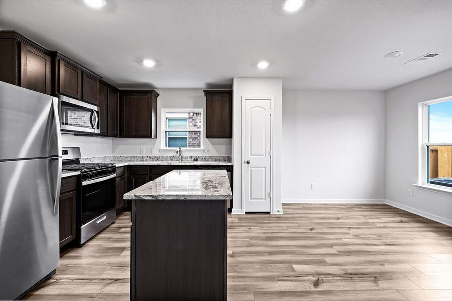 Kitchen with a center island, appliances with stainless steel finishes, light wood-type flooring, and a healthy amount of sunlight