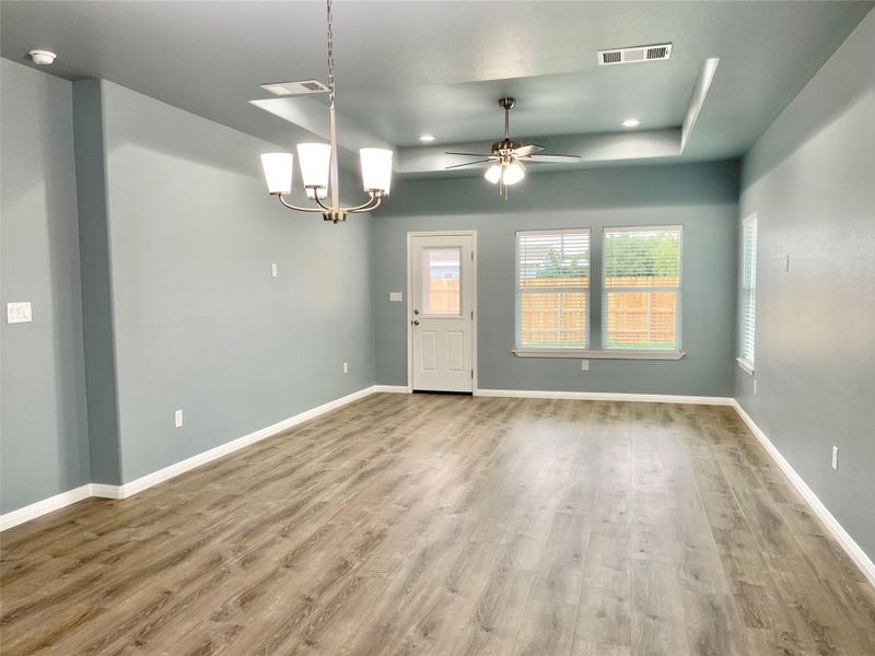 A spacious living area featuring contemporary lighting, recessed lights, and durable laminate flooring.