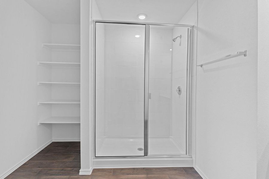 Full bath featuring baseboards, wood finished floors, and a shower stall