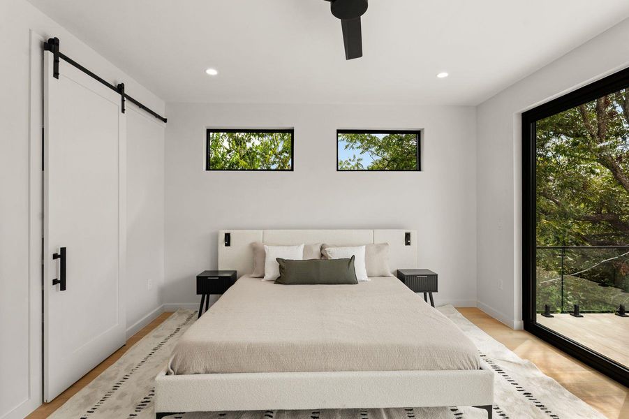 High ceilings, sliding glass doors, and light wood flooring define this contemporary bedroom.