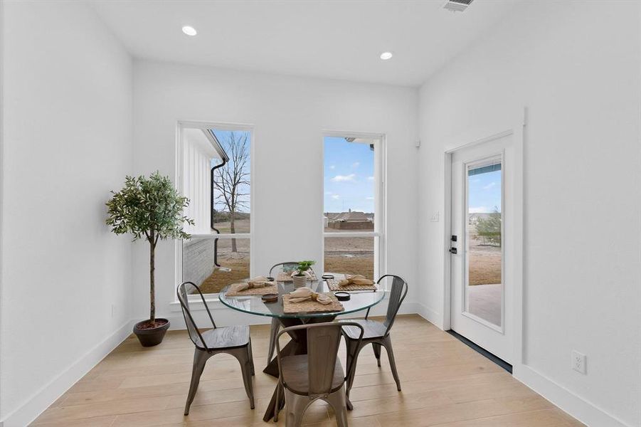 Dining room with light wood finished floors and recessed lighting