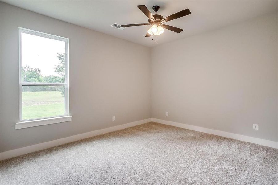Carpeted empty room featuring visible vents, a ceiling fan, and baseboards Carpeted empty room featuring visible vents, a ceiling fan, and baseboards
