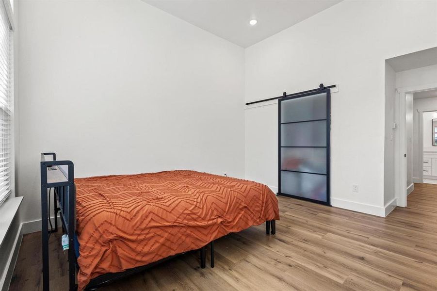 Bedroom featuring a barn door, wood finished floors, and recessed lighting