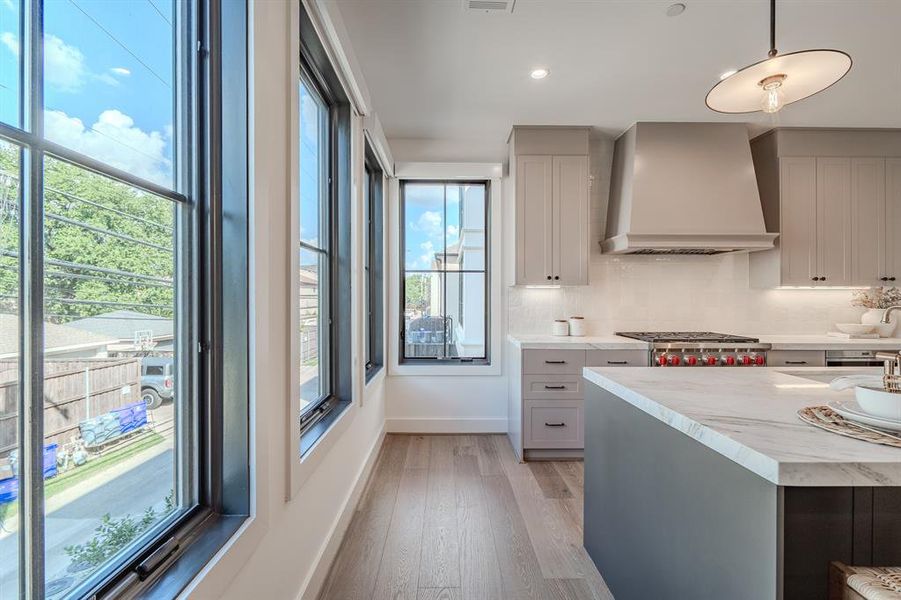 Kitchen featuring premium range hood, backsplash, light wood-style floors, recessed lighting, and gray cabinetry