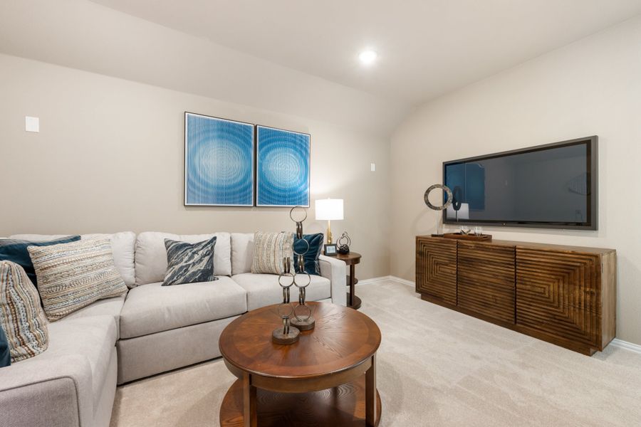Living room with gray sectional sofa, round wood coffee table, wall-mounted TV, and blue abstract wall art