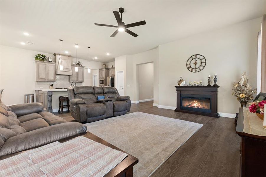 Open-concept living space featuring wood-finish flooring, recessed lighting, and a dark wood mantel fireplace Open-concept living space featuring wood-finish flooring, recessed lighting, and a dark wood mantel fireplace