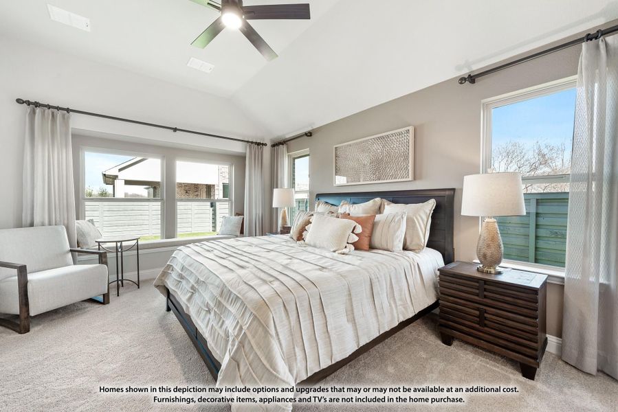 Bedroom with vaulted ceiling, ceiling fan, king bed, carpet flooring, and multiple windows with sheer curtains
