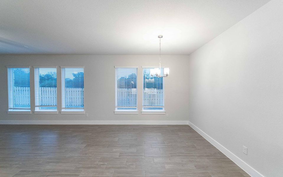 Empty room featuring an inviting chandelier, baseboards, and wood finished floors