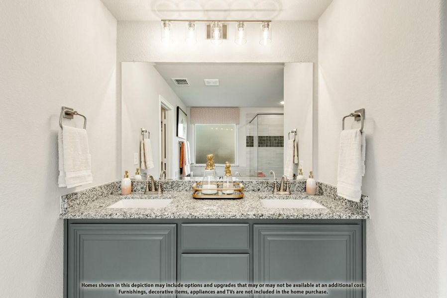 Bathroom vanity with double sinks, granite countertop, gray cabinets, and large mirror with overhead lighting