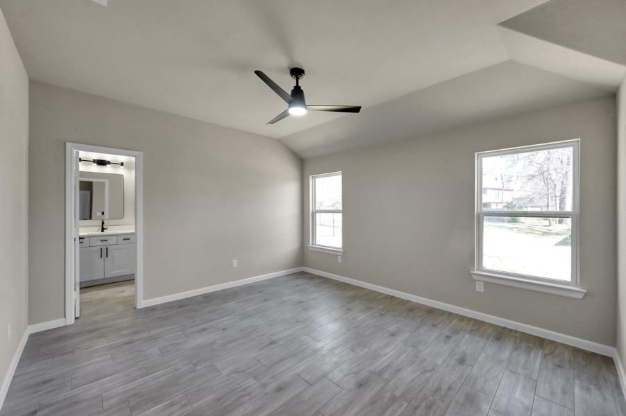 Primary bedroom suite featuring a contemporary ceiling fan, neutral tones, and an attached ensuite bathroom with modern vanity lighting.
