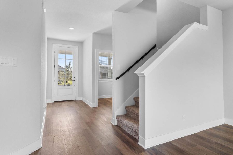 A welcoming entryway with rich wood flooring leads to a carpeted staircase and an abundance of natural light. A welcoming entryway with rich wood flooring leads to a carpeted staircase and an abundance of natural light.
