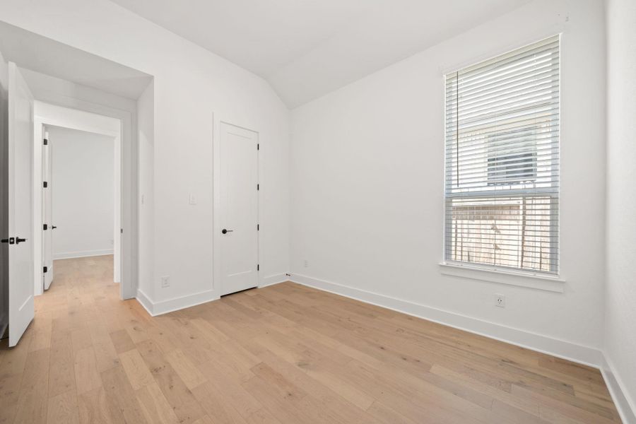 Unfurnished bedroom featuring light wood-type flooring and vaulted ceiling