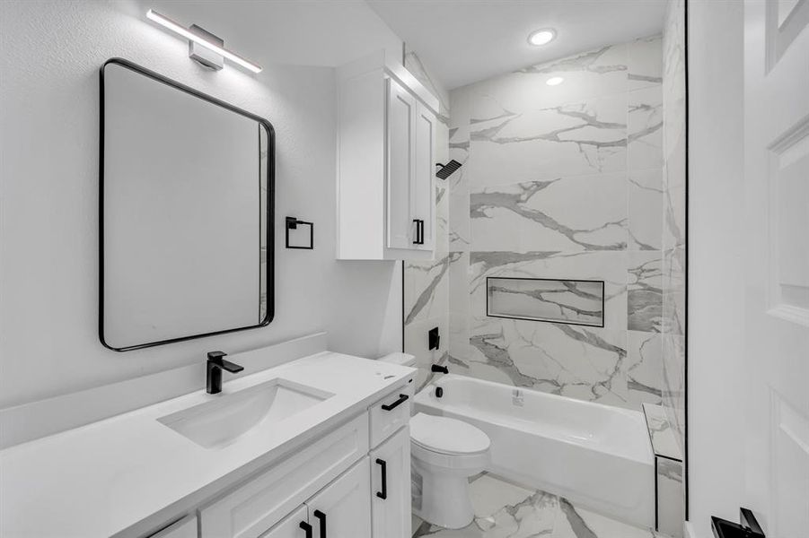 Full bathroom featuring tiled shower / bath, vanity, and toilet