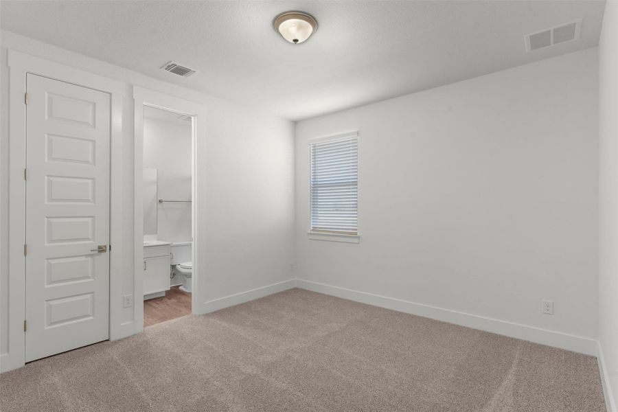Unfurnished bedroom with light carpet and connected bathroom