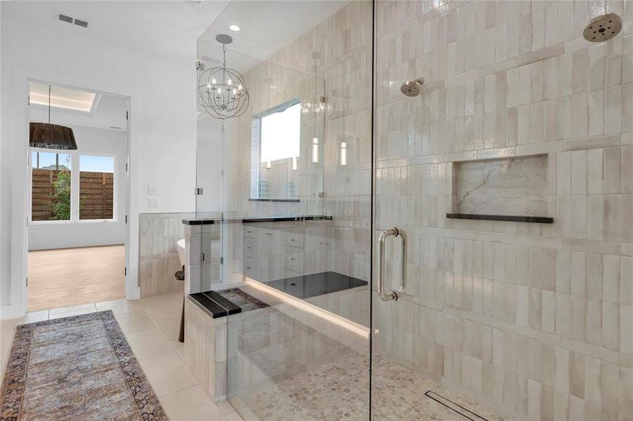 Full bath featuring a shower stall, light tile patterned floors, tile walls, hanging lights, and a wainscoted wall Full bath featuring a shower stall, light tile patterned floors, tile walls, hanging lights, and a wainscoted wall