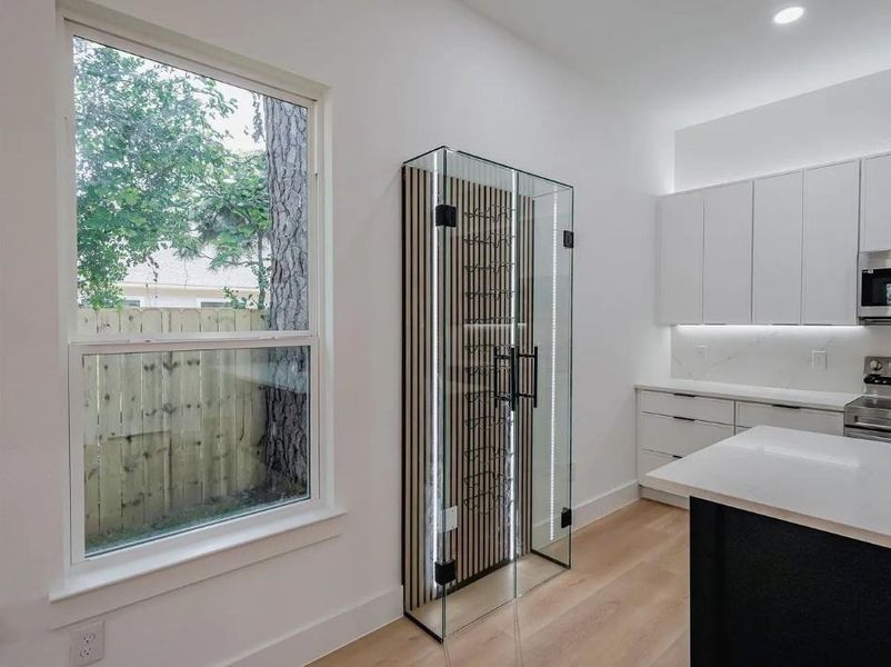 Kitchen featuring white cabinets, stainless steel appliances, light wood-type flooring, modern cabinets, and dark cabinetry