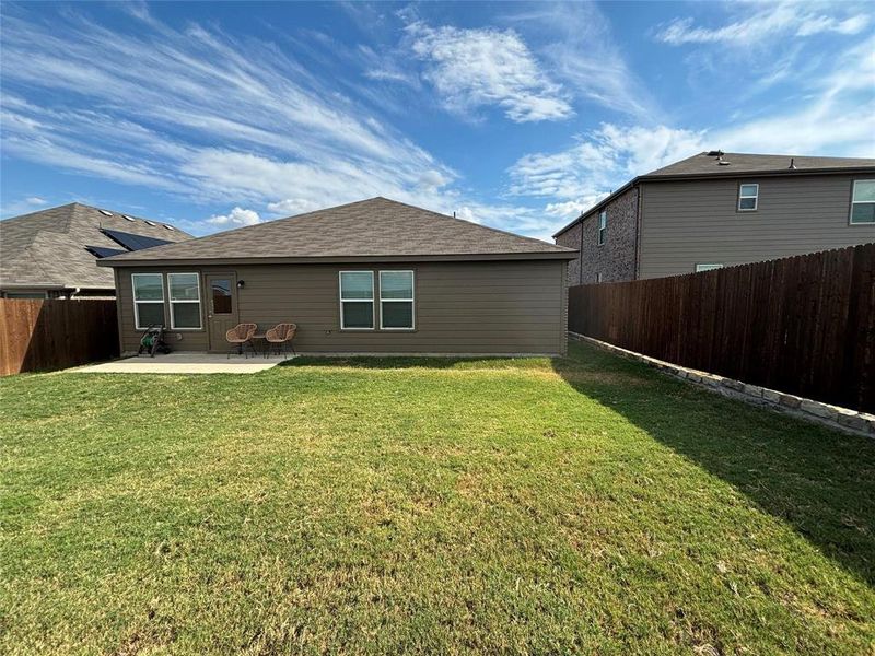 Back of house with a shingled roof, a fenced backyard, and a patio area