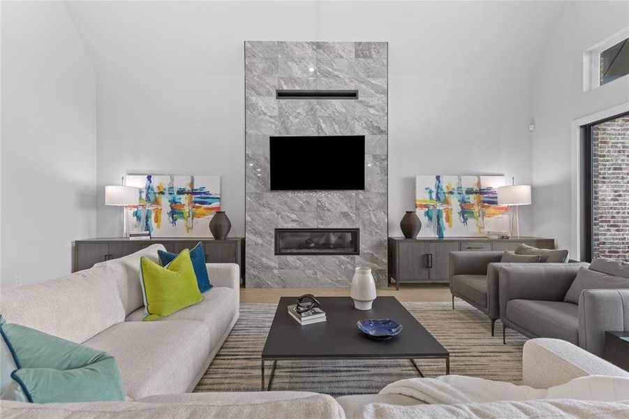 Living room featuring a high end fireplace and high vaulted ceiling