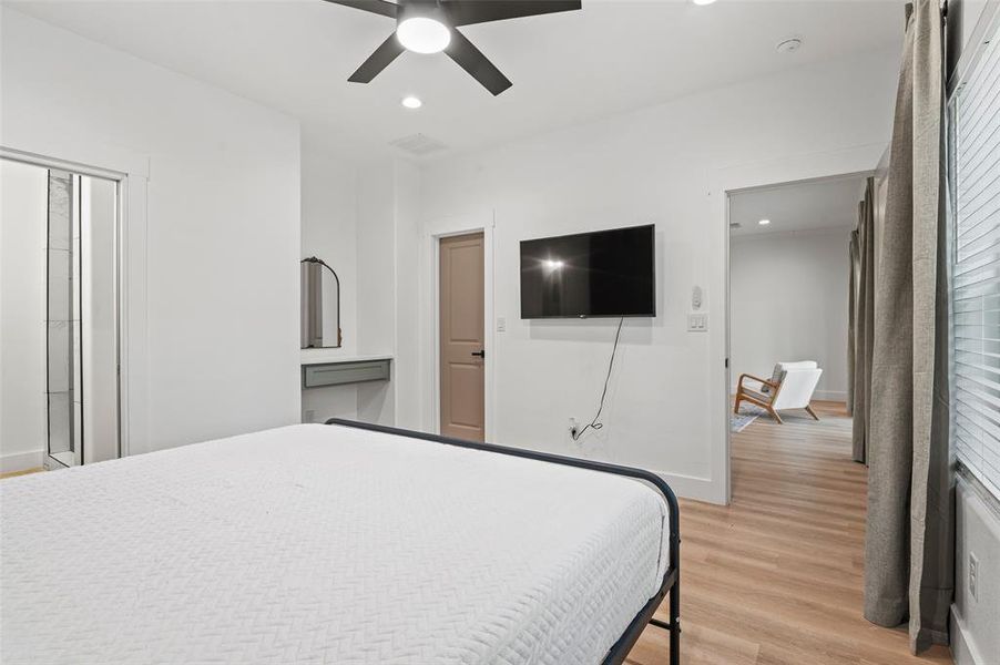 Bedroom with connected bathroom, ceiling fan, and light wood-type flooring