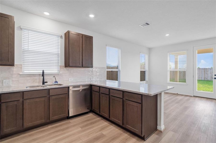 This spacious kitchen features high ceilings, stained wood cabinets, granite countertops, SS appliances, modern tile backsplash, recessed lighting, extended countertop for breakfast bar, and pantry all overlooking your huge family room.