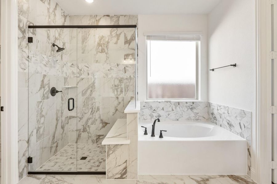 Bathroom with marble tile walls, glass-enclosed shower, and soaking tub with black fixtures