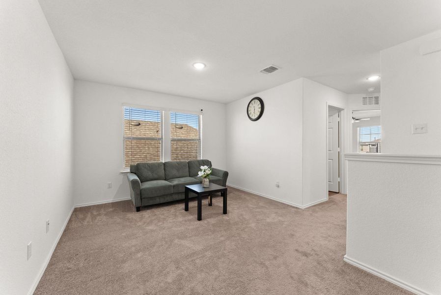 Sitting room featuring light carpet, baseboards, visible vents, and a wealth of natural light