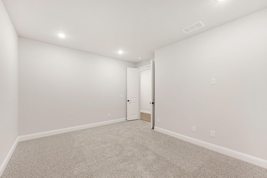 Empty room with white walls, gray carpet, recessed lighting, and open white door Empty room with white walls, gray carpet, recessed lighting, and open white door
