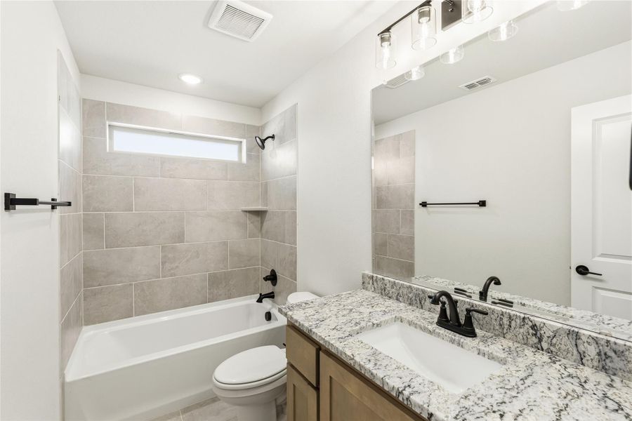 Bathroom with granite vanity, tiled tub-shower combo, and black fixtures
