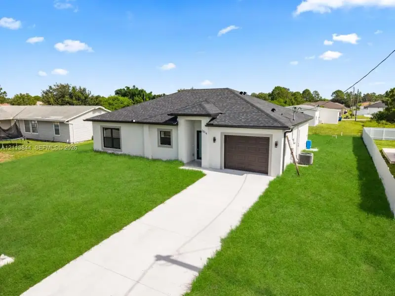 Single-story residence featuring a light-toned stucco exterior, dark asphalt shingle roof, attached garage with a segmented door, and a concrete driveway Single-story residence featuring a light-toned stucco exterior, dark asphalt shingle roof, attached garage with a segmented door, and a concrete driveway