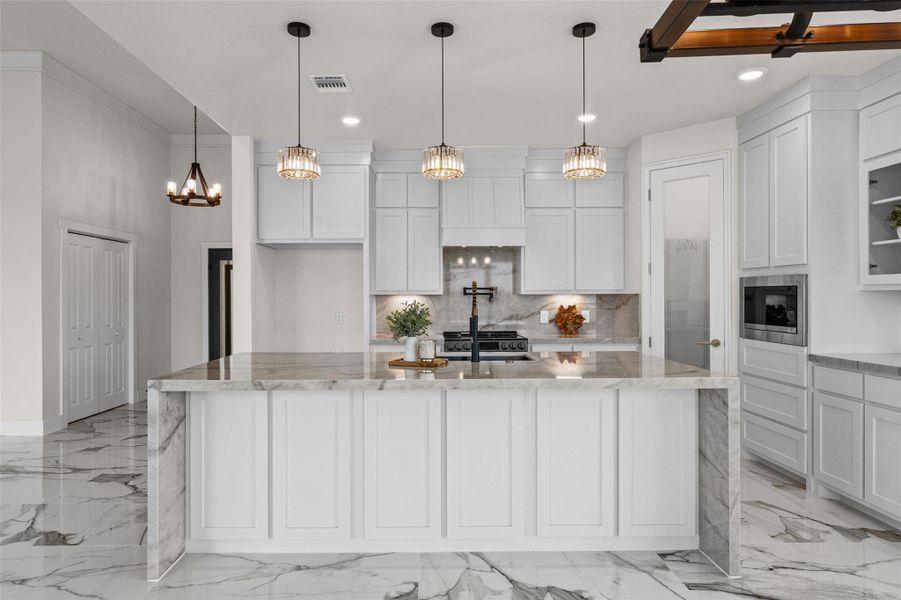 Polished tile flooring and waterfall stone countertops define this elegant culinary space.
