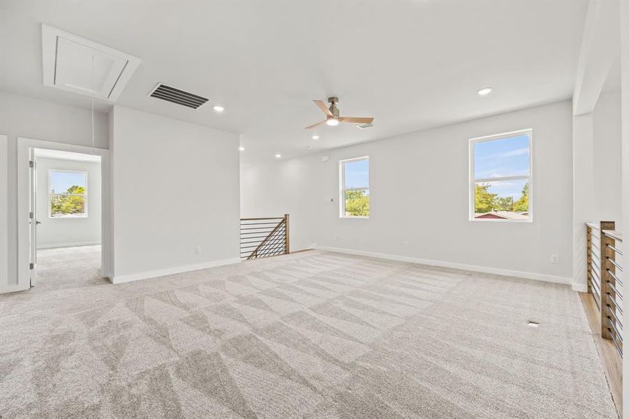 Unfurnished room featuring a healthy amount of sunlight, light colored carpet, and ceiling fan