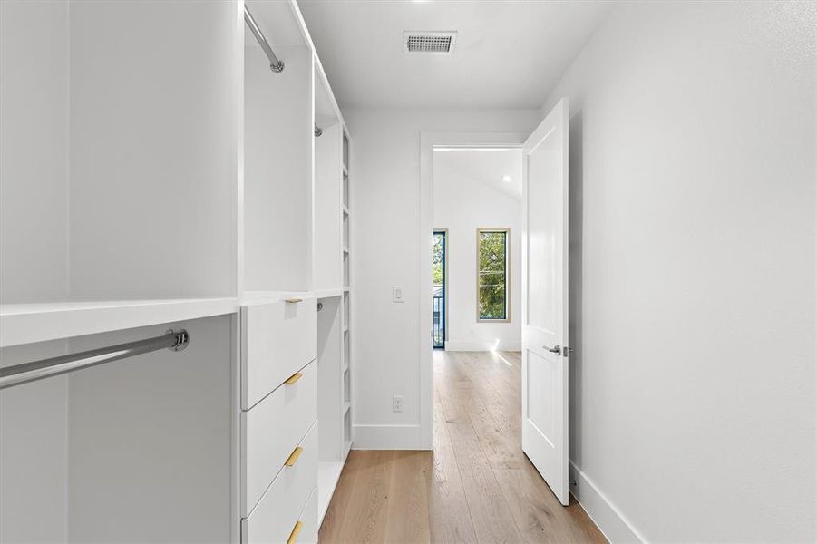 Walk in closet with light hardwood / wood-style floors