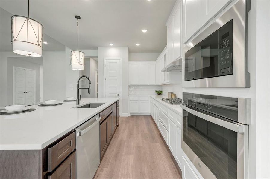 Contemporary kitchen featuring a large island with white countertops, dark wood-finish cabinetry, and a stainless steel sink with a gooseneck faucet