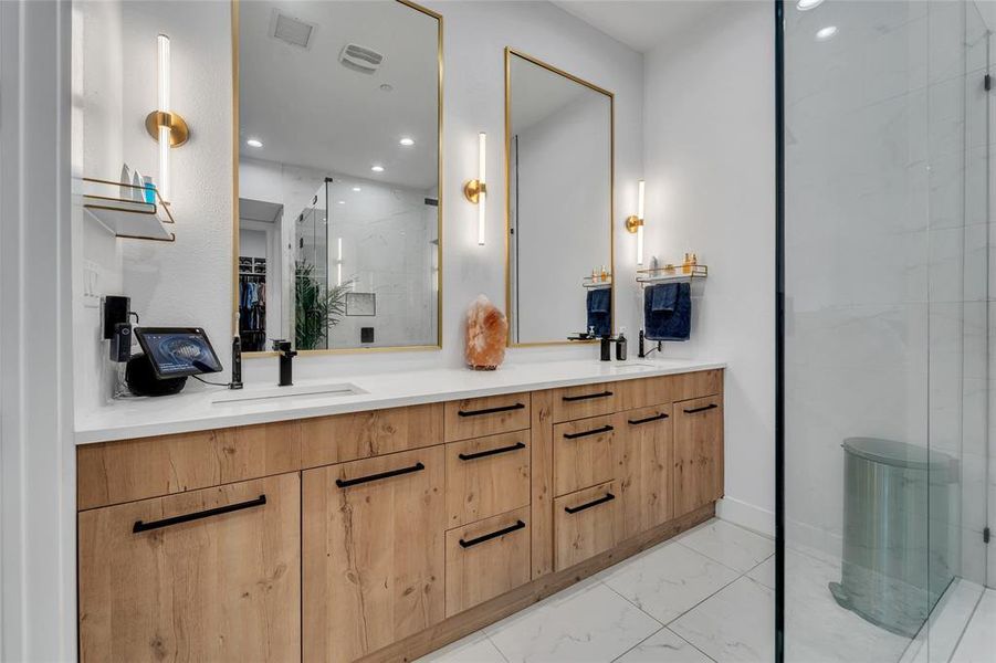 Full bathroom with a stall shower, light marble finish floors, double vanity, a walk in closet, and recessed lighting Full bathroom with a stall shower, light marble finish floors, double vanity, a walk in closet, and recessed lighting
