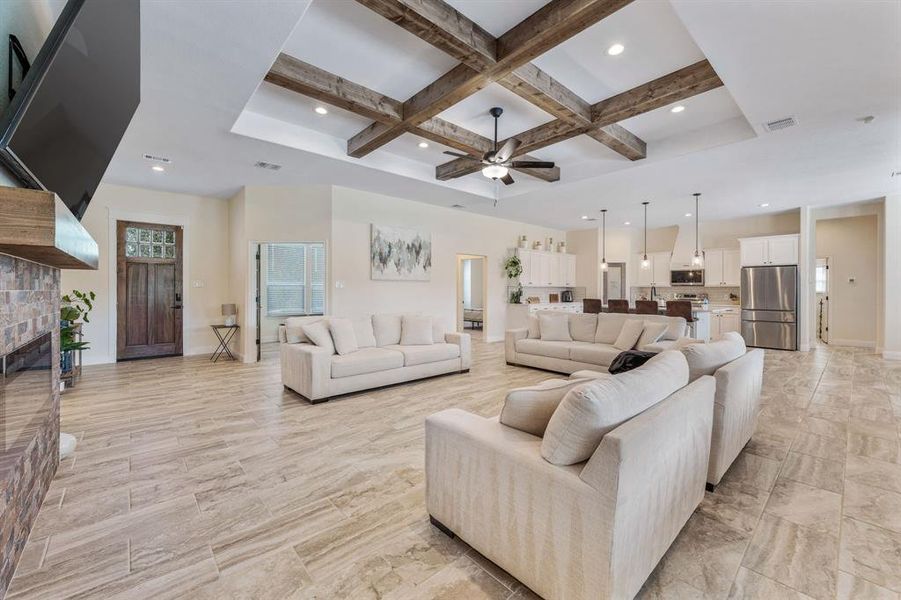 Living room with coffered ceiling, beam ceiling, recessed lighting, a ceiling fan, and a glass covered fireplace Living room with coffered ceiling, beam ceiling, recessed lighting, a ceiling fan, and a glass covered fireplace