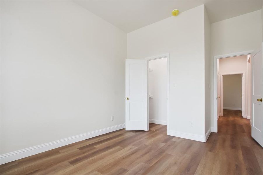 Unfurnished bedroom featuring hardwood / wood-style floors and high vaulted ceiling