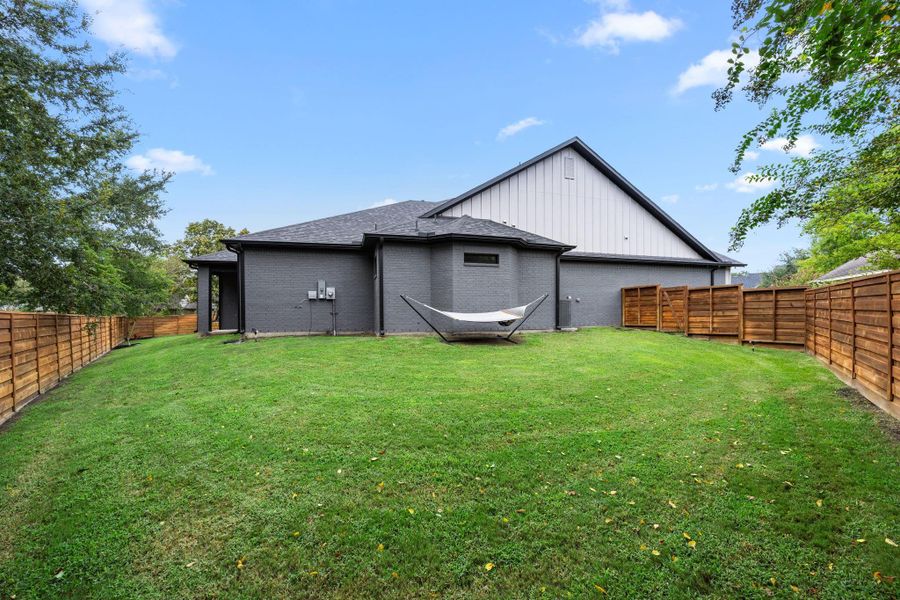 This photo showcases a spacious backyard with a neatly trimmed lawn and cedar fence. The modern home exterior is painted in dark tones, offering a sleek and private outdoor space. This photo showcases a spacious backyard with a neatly trimmed lawn and cedar fence. The modern home exterior is painted in dark tones, offering a sleek and private outdoor space.