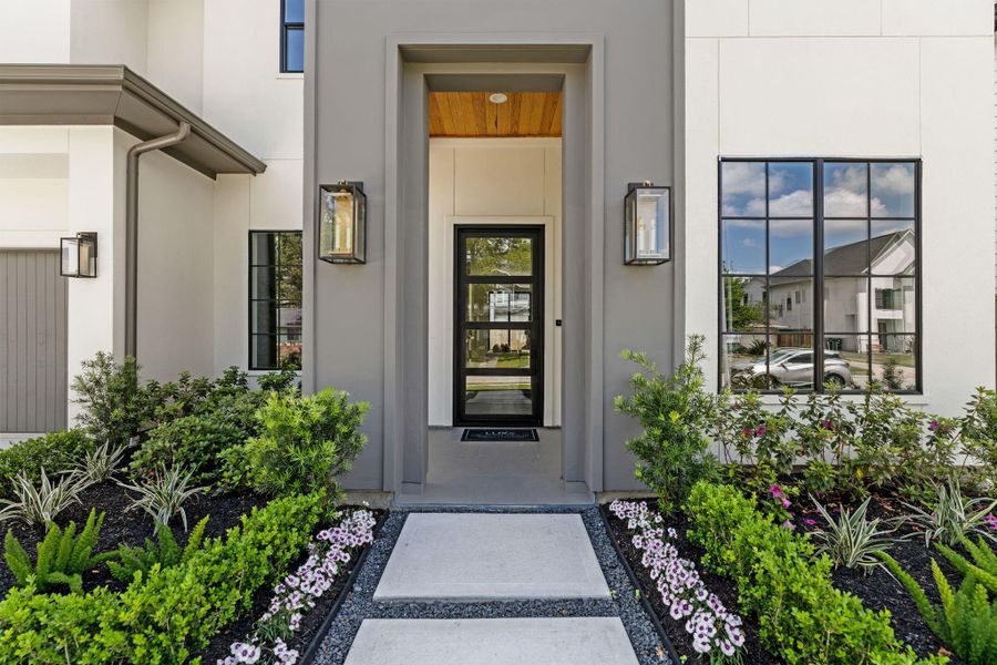 Dark stucco accents,lush landscaping, an oversized steel front door and warm wood tones greet you before you even step inside.