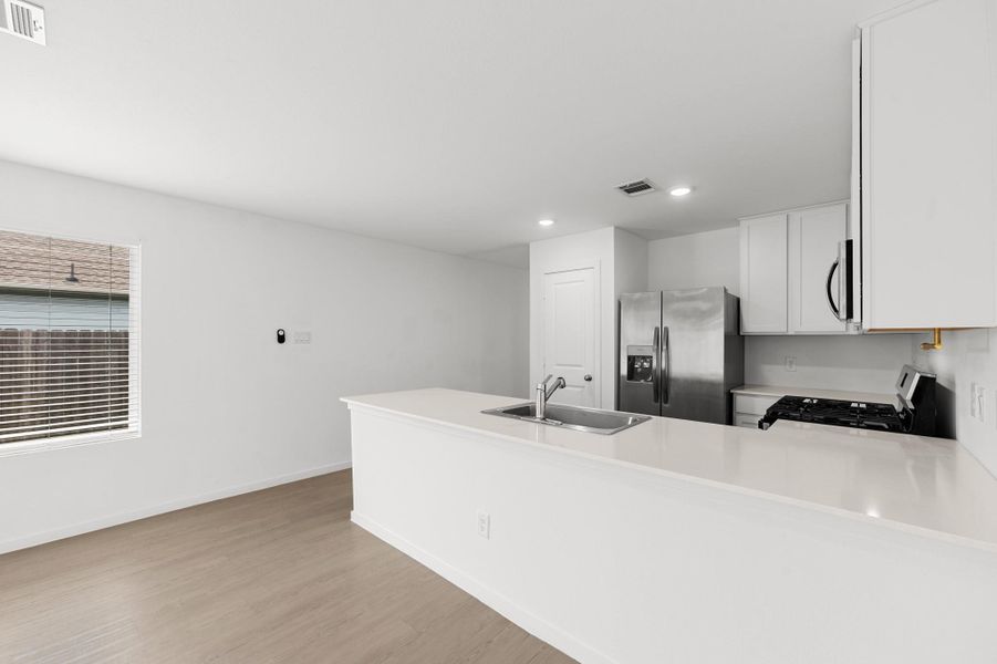 Kitchen & Dining Area – Bright kitchen features a spacious peninsula with an integrated sink and generous counter space, opening to an adjacent dining area with a large window for natural light. Kitchen & Dining Area – Bright kitchen features a spacious peninsula with an integrated sink and generous counter space, opening to an adjacent dining area with a large window for natural light.