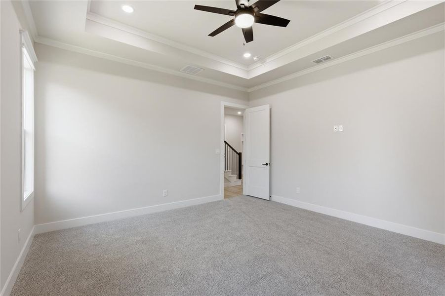 Carpeted room featuring a tray ceiling with recessed lighting and a ceiling fan, white baseboards, and a window for natural light