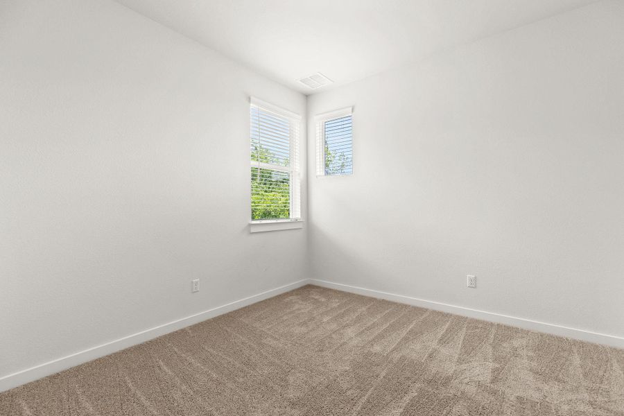 Two large windows illuminate this carpeted room, offering serene views of green foliage. Two large windows illuminate this carpeted room, offering serene views of green foliage.